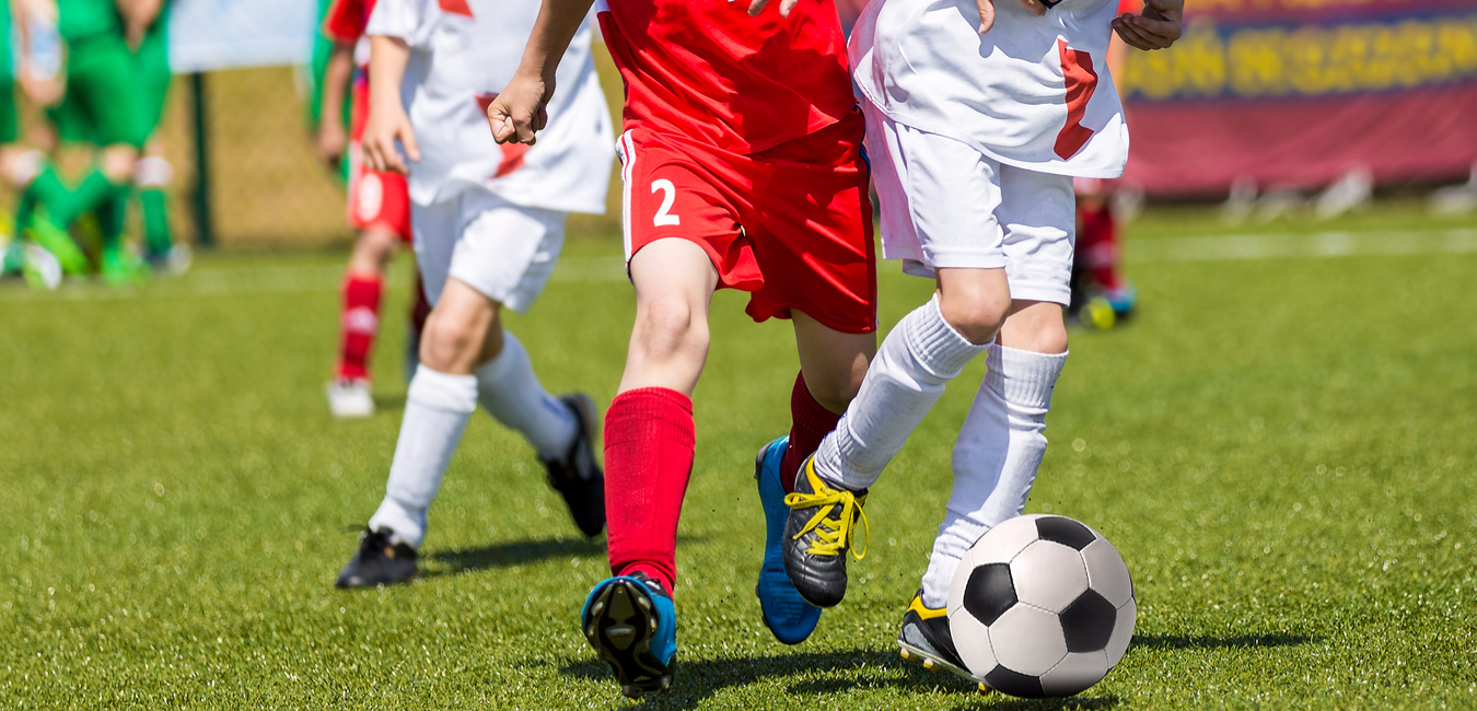 Soccer players in red and white uniforms on the field kicking soccer ball