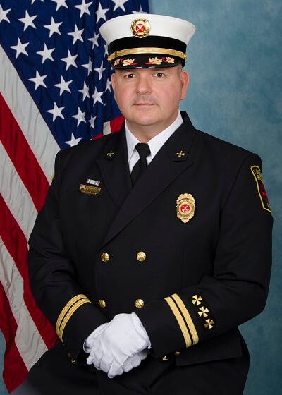 Man in military uniform in front of flag