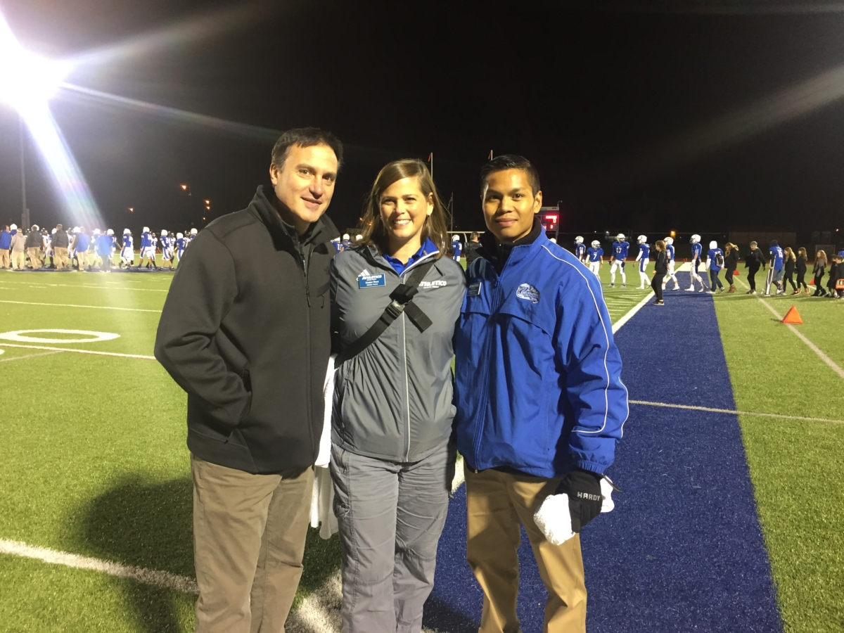Dr. Chams standing with man and woman on football field at night