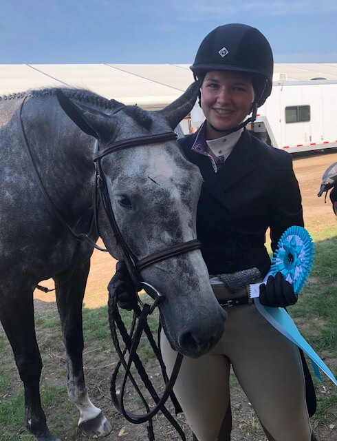 Girl smiling and posing with grey horse