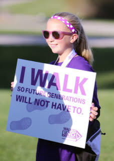 Girl in purple clothes outside holding sign
