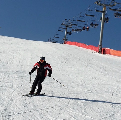 man in red and black jacket skiing down snow covered hill