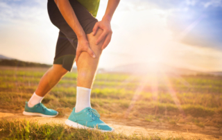 man holding his knee in pain while out for a run outside