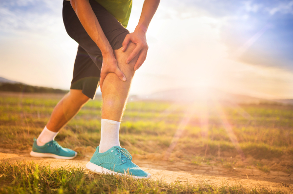 man holding his knee in pain while out for a run outside